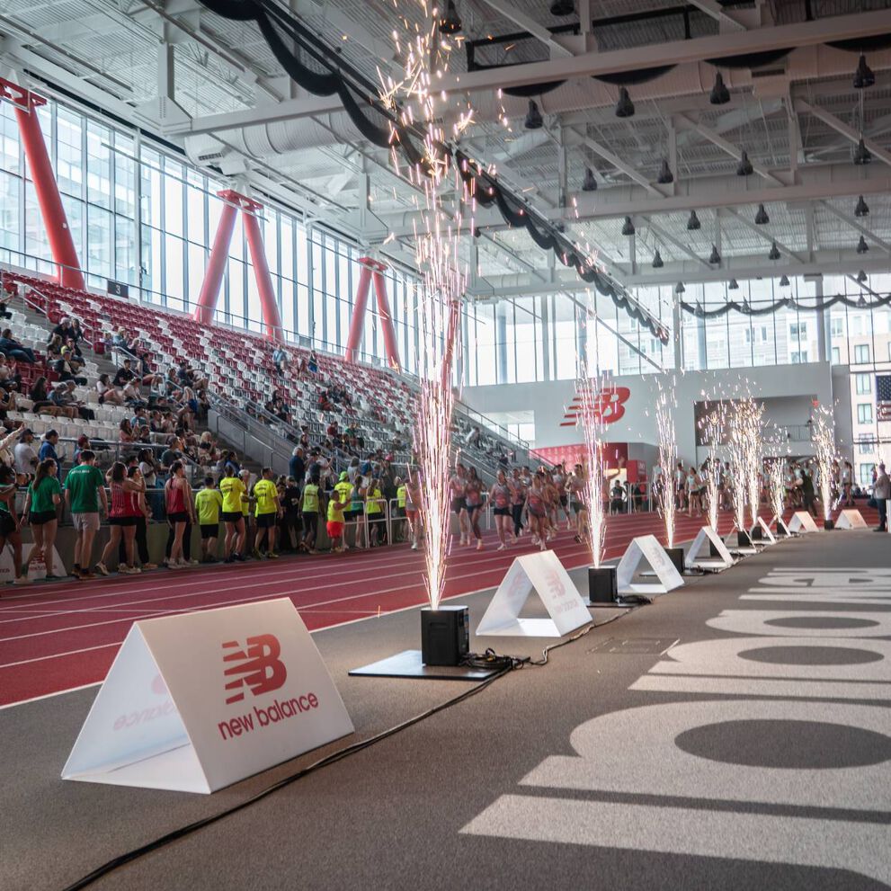 A New Balance event at the track with fireworks going off and people sitting in bleachers